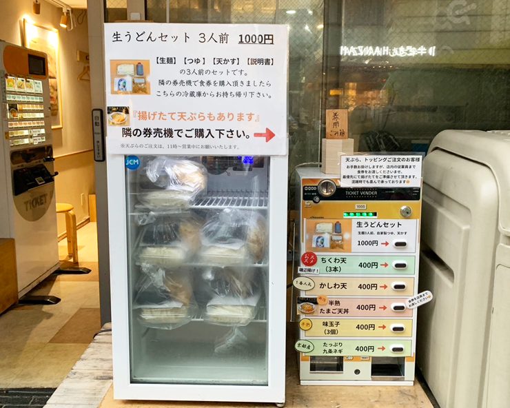 店頭の冷蔵庫と券売機に並ぶテイクアウト用の生うどんセット（3人前1,000円）